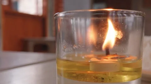 A small floating candle burning brightly inside a clear glass. Video stock 343400711