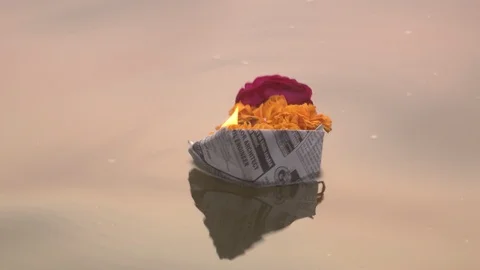 Small flower boat with candle floating in Ganges River at sundown Stock Footage 86760565