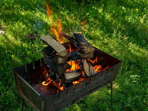 A small folding portable brazier filled with burning wood. Stock Photos