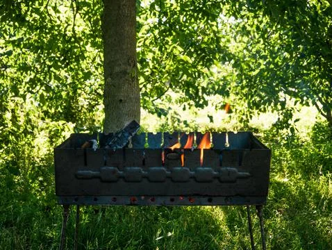 A small folding portable brazier filled with burning wood. Stock Photos