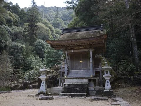 A small forest shrine and the distant red torii in the sea, Japan Stock Photos