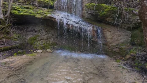 Small forest waterfall cascading over mossy rocks in spring, peaceful woodland s Stock Footage 330120337
