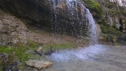 Small forest waterfall cascading over mossy rocks in spring, natural woodland st Stock-Footage 330121099
