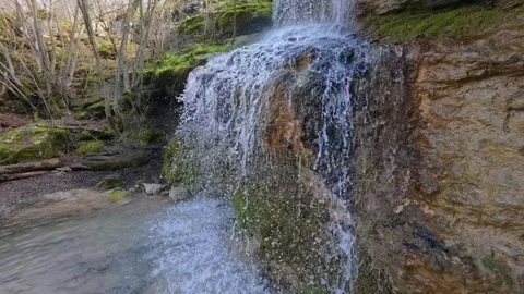 Small forest waterfall cascading over mossy rocks in spring, natural woodland st 库存影片 330121579