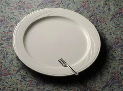 Small fork on empty dinner plate Stock Photos