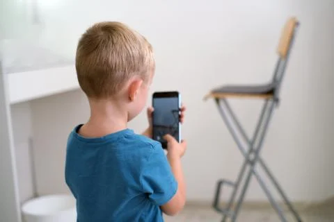 A small four-year-old boy with blond hair and blue eyes takes pictures of som Stock Photos
