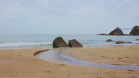 Small freshwater stream flowing through sandy beach into the ocean Stock Footage 338194047