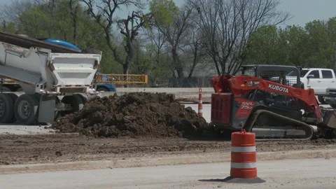 Small frontend loader spreads dirt as truck pulls away, 4K. Stock Footage 151592077