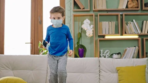 Small funny boy jumping on the sofa while stay at home in quarantine wearing Stock Footage 127712278