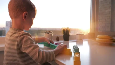 Small Funny Kid Independently Plays Constructor On Table By Window At Sunset Stock Footage 234196470