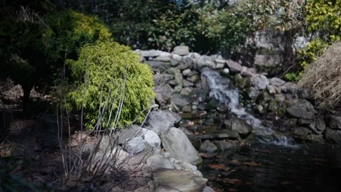 Small garden waterfall cascading over natural rocks Stock Footage 346298678