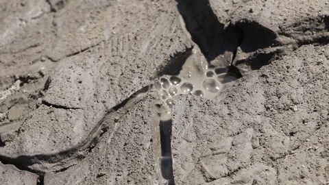 Small gas bubbles erupting through cracked clay inside mud volcano Stock Footage 339270060