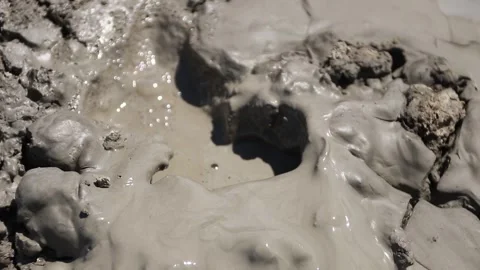 Small gas bubbles erupting through cracked clay inside mud volcano Stock Footage 339270065