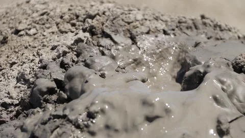 Small gas bubbles erupting through cracked clay inside mud volcano Stock Footage 339270067