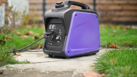 A small gasoline inverter generator with a wire connected to a socket works on Stock Footage 232460106