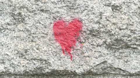 A small generic red heart symbol painted on a wall, heart icon front view, .. Stock Footage 237279802