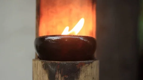 Small gentle flame in a small ceramic bowl on a bamboo stand blowing in the wind Stock Footage 101877002