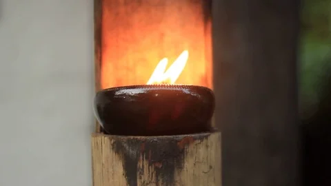 Small gentle flame in a small ceramic bowl on a bamboo stand blowing in the wind Stock Footage 101877003