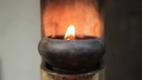 Small gentle flame in a small ceramic bowl on a bamboo stand blowing in the wind Stock Footage 101877009
