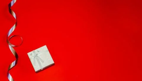 Small gift box with decor of gift blue ribbon on a red background Space for y Stock Photos