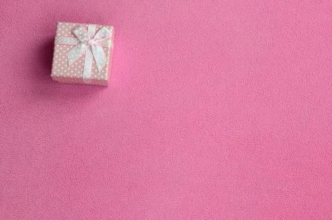 A small gift box in pink with a small bow lies on a blanket of soft and furry Photos
