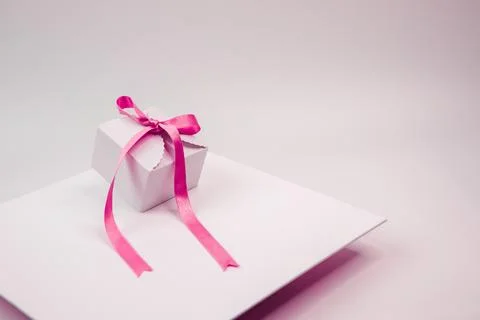 A small gift box sitting on a square white plate with pink ribbon 写真素材