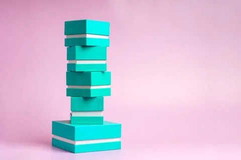 Small gift boxes of blue-green color stand in a stack on a pink background Stock Photos