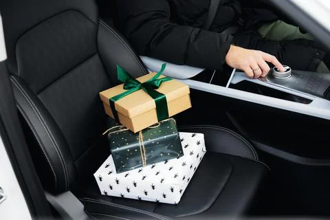 Small gift boxes stand on the front seat of the car Stock Photos