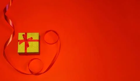 Small gift with red bow on red background. Free space for your text. Stock Photos