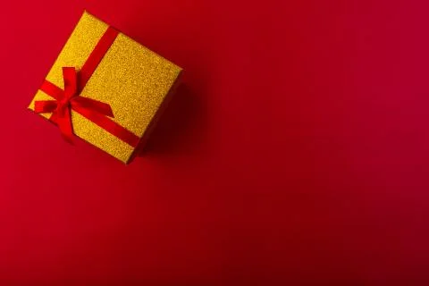 Small gift with red bow on red background. Free space for your text. Stock Photos