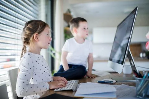 Small girl and boy using computer indoors at home. Corona virus and quarantine Stock Photos
