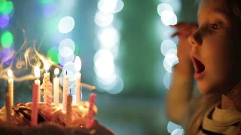 A small girl blowing out candles on the cake. Slow motion. Stock Footage