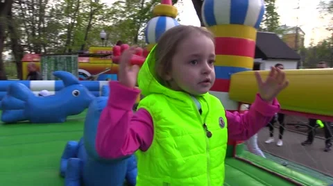 Small girl is going to play on inflatable trampoline in the children's amusement Stock Footage 68441372