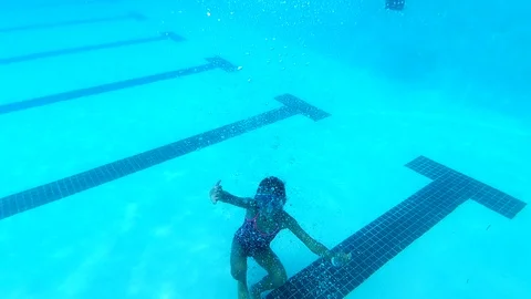 Small girl kicks off the bottom of the pool slow mo Stockbeeldmateriaal 109220121
