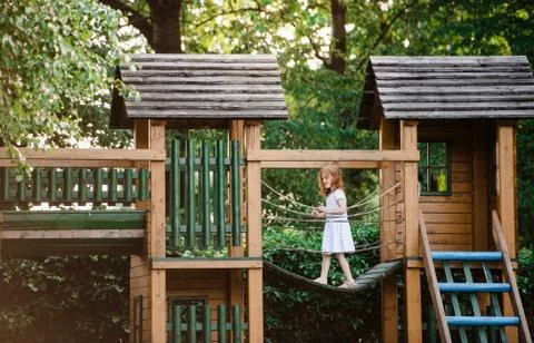Small girl outdoors on wooden playground in garden in summer, playing. Stock Photos