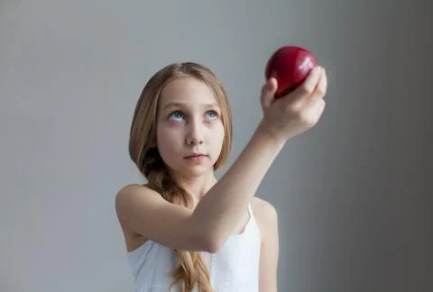 Small girl with red apple on gray background Stock Photos