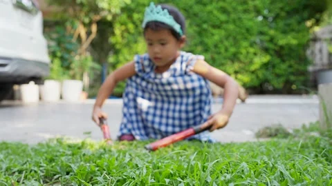 Small girl using grass shears cutting the grass at garden. Vídeo Stock 224698272