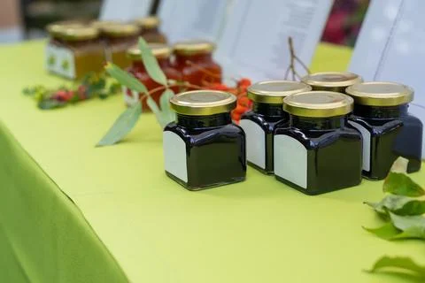 Small glass jars filled with assorted jam displayed at local food market. Hom Foto stock
