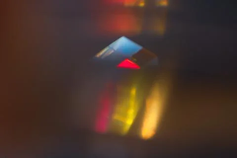 Small glass prism casting red yellow and blue refracted light on dark surfa.. Stock Photos