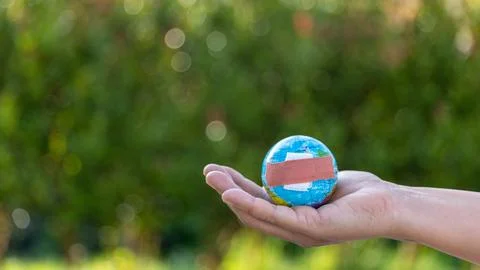 The small globe, earth is on hand, grass, leaf. The globe has maps on it an.. Stock Photos