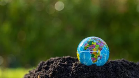 The small globe, earth is on hand, grass, leaf. The globe has maps on it an.. Stock Photos