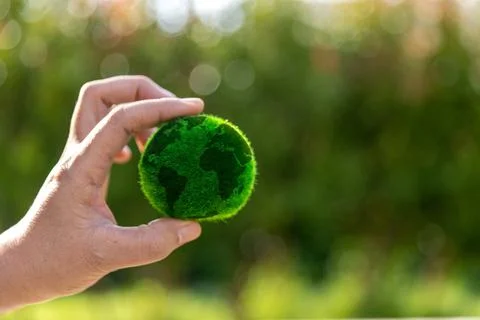 The small globe, earth is on hand, grass, leaf. The globe has maps on it an.. Stock Photos