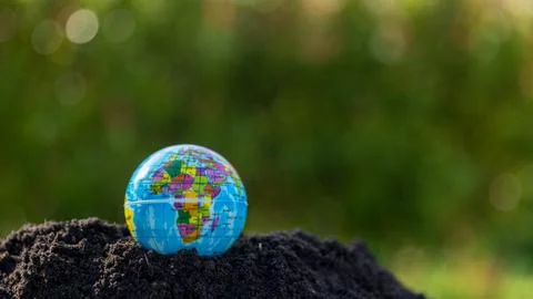 The small globe, earth is on hand, grass, leaf. The globe has maps on it an.. Stock Photos