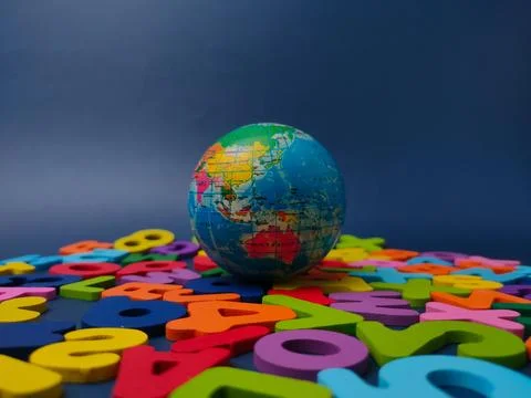A small globe sits centered amidst a wide arrangement of colorful wooden le.. Stock Photos