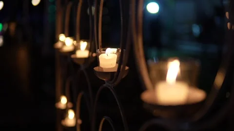 Small glowing candles arranged in a decorative metal frame at night Stock Footage 335270778