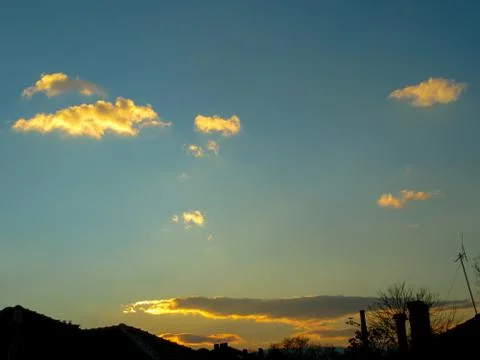 Small gold clouds over the city before sunset. Stock Photos