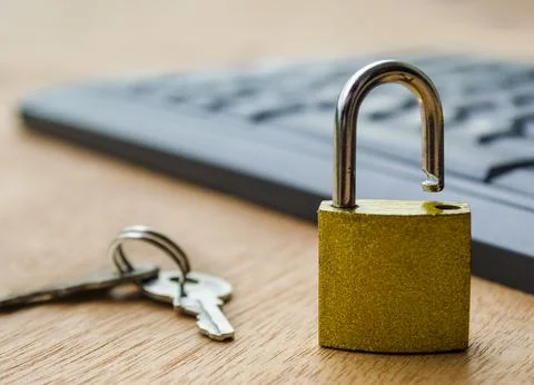 A small golden padlock standing open on a computer keyboard symbolizing cyb.. Stock Photos