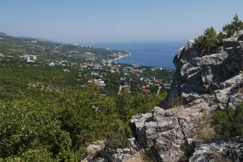 Small grass-covered rocks on the background of a beautiful coastal town Stock Photos