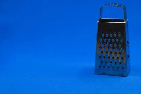 A small grater on a blue background in the right corner. Stock Photos