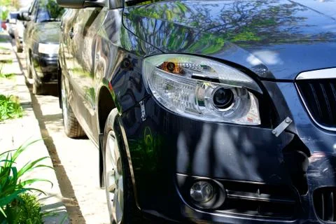 A small gray car with a damaged headlight after a collision Stock Photos
